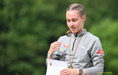 Eine Person mit Medaille betrachtet ihre Urkunde während der Siegerehrung bei der Rheinland-Pfalz-Meisterschaft in Konz.