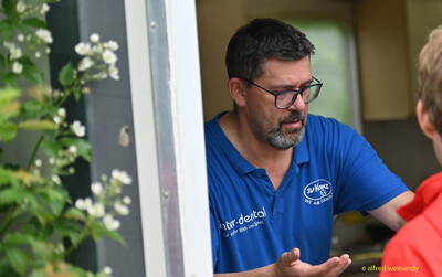 Eine Person im blauen Vereinspolo unterhält sich am Verpflegungsstand bei der Rheinland-Pfalz-Meisterschaft in Konz.