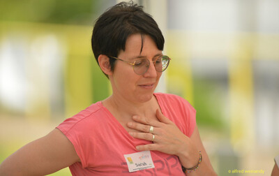 Eine Person mit Brille und Namensschild im Porträt am Rand der Rheinland-Meisterschaft im Mehrkampf der TG Konz in Konz.