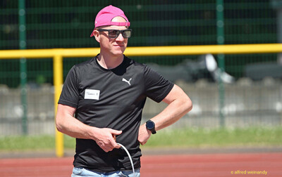 Eine Person mit pinkfarbener Kappe und Sonnenbrille steht auf der Laufbahn bei der Regionsmeisterschaft der Region Trier in Konz.