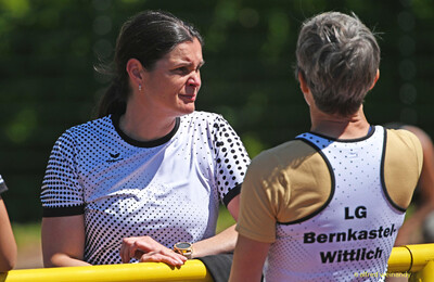 Zwei Personen in Vereinstrikots unterhalten sich am Rand des Sportgeländes bei der Regionsmeisterschaft der Region Trier in Konz.