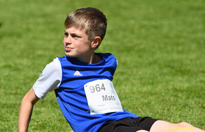 Eine junge Person mit Startnummer sitzt im Gras bei der Regionsmeisterschaft der Region Trier in Konz.