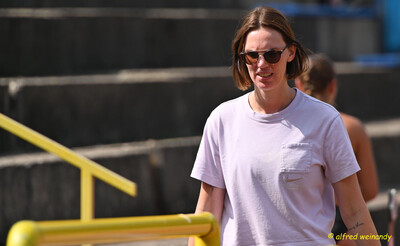 Eine Person mit Sonnenbrille geht neben der Tribüne über die Anlage beim Mehrkampf der TG Konz in Konz.