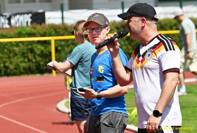Zwei Helfende mit Mikrofon und Stoppuhr organisieren den Wettkampf beim Kinderleichtathletik-Sportfest der TG Konz im Saar-Mosel-Stadion in Konz