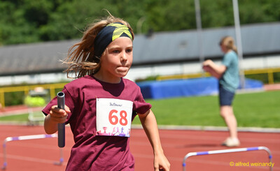 Ein Kind läuft mit dem Staffelholz in der Hand über die Bahn beim Kinderleichtathletik-Sportfest der TG Konz im Saar-Mosel-Stadion in Konz