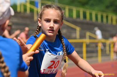 Ein Kind übergibt bei der Staffel das orangene Staffelholz beim Kinderleichtathletik-Sportfest der TG Konz im Saar-Mosel-Stadion in Konz