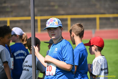 Ein Kind hält eine Stange fest und wartet mit anderen Kindern beim Kinderleichtathletik-Sportfest der TG Konz im Saar-Mosel-Stadion in Konz