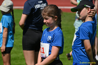 Kinder warten in ihren blauen Vereinstrikots am Rand der Anlage beim Kinderleichtathletik-Sportfest der TG Konz im Saar-Mosel-Stadion in Konz