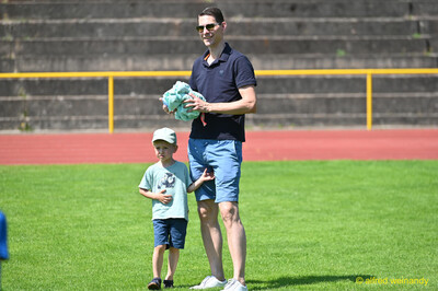 Eine erwachsene Person geht mit einem Kind an der Hand über den Rasen beim Kinderleichtathletik-Sportfest der TG Konz im Saar-Mosel-Stadion in Konz