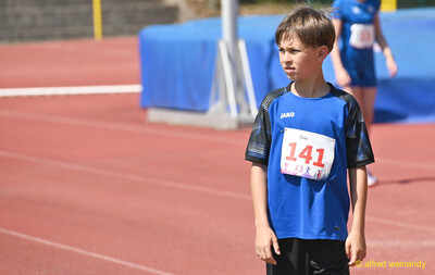 Ein Kind mit der Startnummer 141 wartet vor der blauen Hochsprunganlage beim Kinderleichtathletik-Sportfest der TG Konz im Saar-Mosel-Stadion in Konz