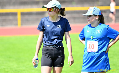 Zwei Kinder gehen mit Trinkflasche und Trillerpfeife über den Platz beim Kinderleichtathletik-Sportfest der TG Konz im Saar-Mosel-Stadion in Konz
