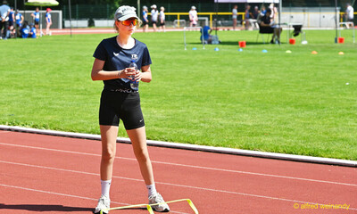 Ein Kind steht mit einer Trinkflasche auf der Laufbahn neben einer Hürde beim Kinderleichtathletik-Sportfest der TG Konz im Saar-Mosel-Stadion in Konz