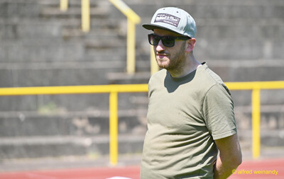 Eine Betreuungsperson mit Cap und Sonnenbrille beobachtet das Geschehen beim Kinderleichtathletik-Sportfest der TG Konz im Saar-Mosel-Stadion in Konz