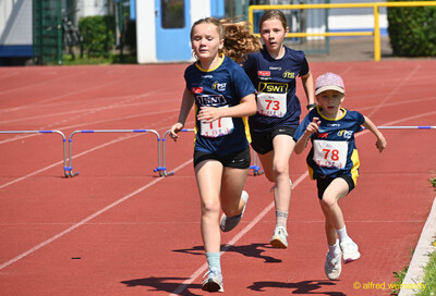 Drei Kinder sprinten dicht nebeneinander über die rote Laufbahn beim Kinderleichtathletik-Sportfest der TG Konz im Saar-Mosel-Stadion in Konz