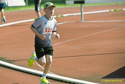 Ein Kind mit Cap läuft konzentriert allein über die Laufbahn beim Kinderleichtathletik-Sportfest der TG Konz im Saar-Mosel-Stadion in Konz
